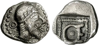 Hémiobole de Thémistocle en Magnésie (vers 465-459 av. J.-C.) où il est montré portant un bonnet serré avec une couronne d'olivier (une coiffe similaire peut être vue sur la monnaie de Kherei (en))[79]. Cela reflète peut-être les bonnets des satrapes achéménides, comme on le voit dans la Tête d'Héraclée du Pont (en)[80]. Les initiales « ΘΕ » sont visibles autour du portrait et au revers[79].