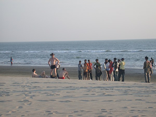 Three Ukrainian men, wearing trunks and briefs, attract attention for immodesty relative to the local norm in Cox's Bazar, Bangladesh.
