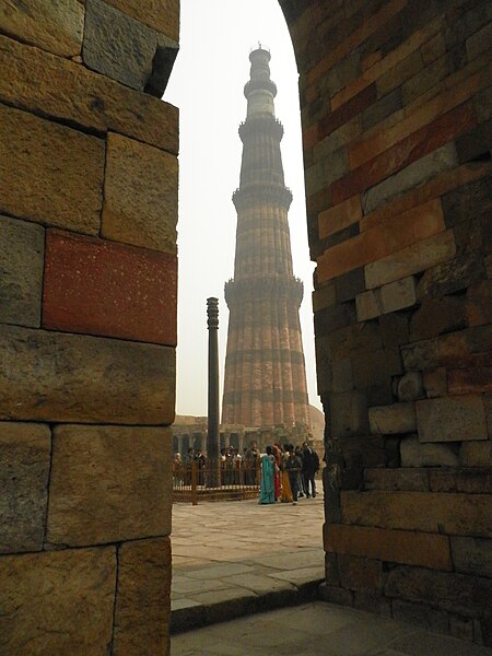 File:Iron pillar and a view of qutub.JPG