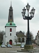 This is a photograph of an architectural monument. Kandelaber (Hintergrund: Stadtkirche) 53°47′17″N 9°25′26″E﻿ / ﻿Am Markt﻿ / 53.788119; 9.423979 Entstehungsjahr: 1869   Foto: 2012  