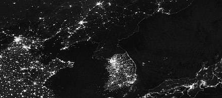 Aerial night view of the Korean Peninsula showing South Korea illuminated and few lights in Communist North Korea