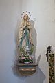 Barevná fotografie sochy Panny Marie, která stojí na konzole v levém rohu u oltáře
