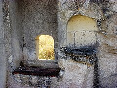 Photographie en couleurs d'une petite ouverture et d'un évier en pierre dans un mur.