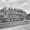 Boerderij met voorgevel met ingezwenkte zijkanten, deuromlijsting met pilasters en zesruitsvensters onder wolfsdak