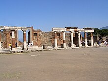 Ruins of the building funded by Eumachia, with portions of the inscription visible on the horizontal light-colored stone Pompeje 001.jpg