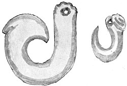 A greenstone carving in the shape of a fish hook. Also shown is a smaller similar version