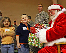 Santa Claus giving gifts to children, a common folk practice associated with Christmas in Western nations Pvt. Evan Allen Dancer, center, smiles as Santa Claus, right, hands gifts to Destiny Hawley and her brother Justin Hawley of Scipio, Ind., during the 3rd Annual Operation Christmas Blessing event at Muscatatuck 111212-A-QU728-005.jpg