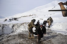 SSG Jonathan Hill, from the 438th Air Expeditionary Advisory Squadron, directs villagers to his helicopter on a rescue mission in Badakshan province, Afghanistan after an avalanche.jpg