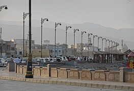 A street along the beach of the Gulf of Oman, with the Eastern Hajar Mountains in the background