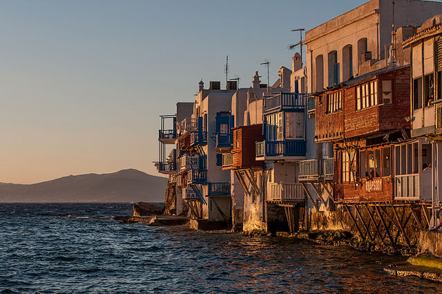 Заходящее солнце освещает дома на берегу острова Миконос в Эгейском море