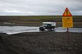 Hier fährt ein Auto in Island über eine flache Stelle im Fluss.