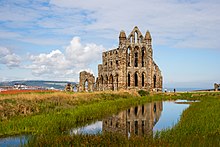 The ruins of Whitby Abbey are reflected in the abbey pond