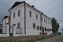 Photographie d'une maison blanche possédant deux étages avec un toit en pente noir.