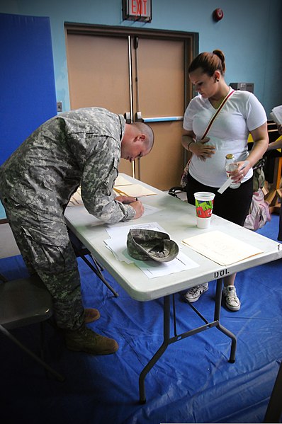 File:A U.S. Soldier, left, assigned to the 501st Special Troops Battalion, 501st Sustainment Brigade fills out paperwork for a civilian role player during training on noncombat evacuation operations during 110818-A-QX270-023.jpg