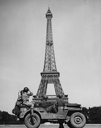 American soldiers look at the French tricolour flying from the Eiffel Tower.