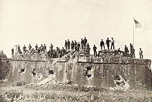 The American flag is raised over Fort Santiago after the surrender of Manila on August 13. American troops raising the Flag at Fort San Antonio De Abad, Malate, Philippines (1899).jpg