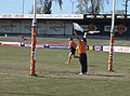 The goal umpire signals a goal with two white flags, while the field umpire makes his way back to the centre of the ground for the next ball up. Taken at the Grand Final of the Victorian Women's Football League, Division 1 Reserves.