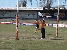 A goal umpire signalling a goal with two white flags, and a Boundary umpire. Australian Rules football umpire goal.JPG