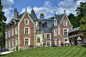Photographie d'une grande demeure de style Renaissance, en briques rouges et aux toits d'ardoise.