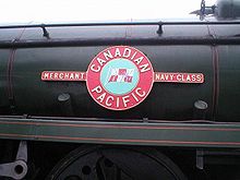 Une plaque signalétique en métal émaillé de classe Marine marchande montée sur le côté de la chaudière de la locomotive.  La plaque signalétique comprend un cercle, contenant une image du drapeau de la compagnie maritime, et deux rectangles de chaque côté contenant le nom de la classe.  Dans un cercle plus large bordant le drapeau central se trouve le nom de la compagnie maritime.