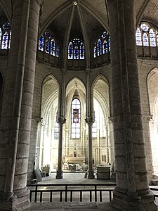 Chapelle contenant quelques statues et autres sculptures, surmontée de trois vitraux décoratifs.