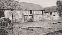 Photographie en noir et blanc d'une ferme et de sa cour.