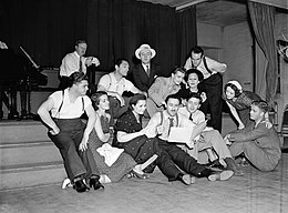 A group of people reading from a book, probably singing together