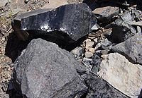 Obsidiana (brilhante), pedra-pomes (acinzentada, à frente) e riólito (claro, à direita)