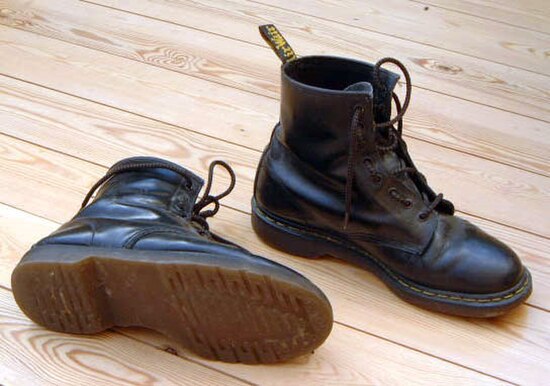 A pair of classic black leather Griggs' Dr. Martens boots, with distinctive yellow stitching around the sole