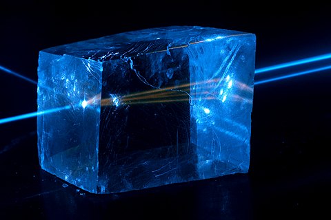 Fluorescentie en dubbele lichtbreking van een 445 nm laserstraal door een calcietkristal.
