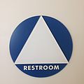 A large white triangle and the word "Restroom". Might not be understood as gender-neutral by all viewers.