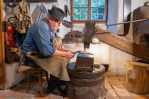 The same trip hammer in operation, shaping a folding knife at the strike area Hammer und Schleiferei zum Kini Schmied am Schwanzhammer-9465.jpg