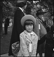 Mladá členka evakuované rodiny čeká na evakuační autobus. Evakuované osoby japonského původu jsou umístěni do internačních táborů, Hayward, Kalifornie, 8. května 1942.