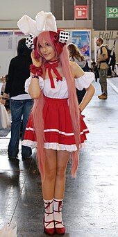 Cosplay d'Ecaflip, avec des habits blancs et rouges. La cosplayeuse porte des chaussures à talons, une jupe, ainsi qu'une coiffe avec des oreilles de lapin.