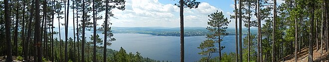 Lac vu d'une montagne avec une forêt au premier plan.