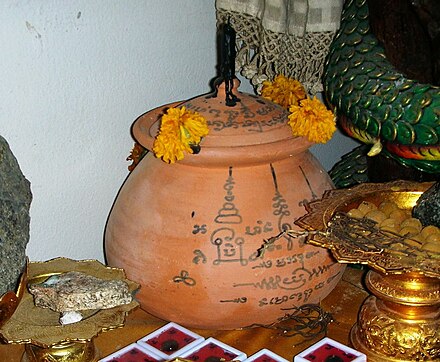 Mo Khao (หม้อข้าว) clay pot with yantra inscriptions and a candle
