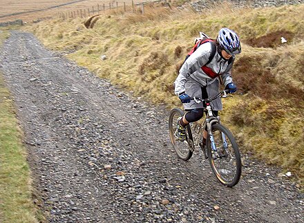 A cross-country mountain biker climbs on an unpaved track