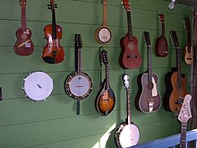 Stringed instruments hanging on a wall. Shown here are 4 Ukuleles, 2 mandolins, a banjo, a guitar, a violin, a Guraitar and a bass guitar. Music wall.jpg