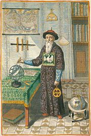 Gravure en couleurs d'un homme à longue barbe blanche coiffé d'un bonnet rond à double tranchant et vêtu d'une longue robe, qui pointe une boussole vers un globe céleste assis sur une table à gauche.