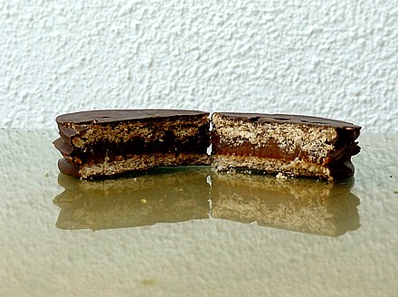 A chocolate-coated alfajor, cut open to show the cookies and filling