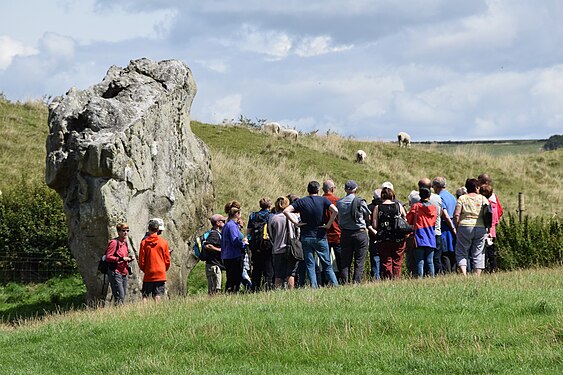 A party of tourists at Avebury listening to a guide