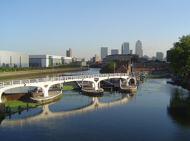 Bow Creek (tidal) (far left) meets the Limehouse Cut (canal, right), at Bow Locks on the Lee Navigation (centre); with a view of London's Docklands