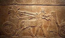 Bas-relief représentant des personnages sur un char tiré par des chevaux, sous un parasol.