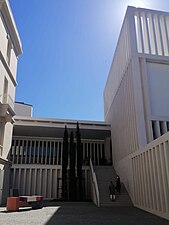 Fachada y escaleras de acceso del nuevo edificio del Museo de Arte Contemporáneo Helga de Alvear con decoración artística y vegetal.