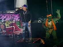 Vanilla Ice (left) performing alongside Michelangelo of the Teenage Mutant Ninja Turtles in 2023. Houston Dash 90s Bash, 2023-10-08 (53255837776) (cropped).jpg