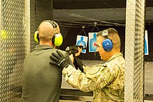 A man shooting an AK-47 at the gun range with the help of a range safety officer on May 1, 2015. Jimmy Harris shooting an AK-47 at Battlefield Vegas on May 1, 2015.jpg