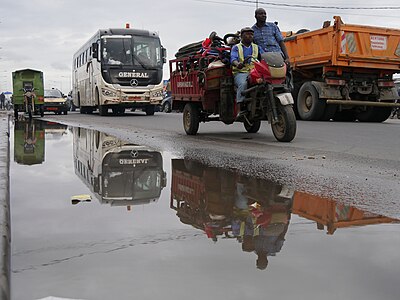 Apres la pluie, le trafic routier reprend dans la rue jallonée de flasques d'eau.