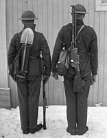 Norsk skytt (höger) och laddare (vänster) till ett 6,5 mm Madsen kulsprutegevär, 1928. Skytten bär kulsprutegeväret på ryggen. Laddaren håller i ett Krag–Jørgensen M/1894 repetergevär.