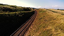 St. Ives Bay Line running above Porth Kidney Sands Railway Line at Porthkidney Beach.jpg