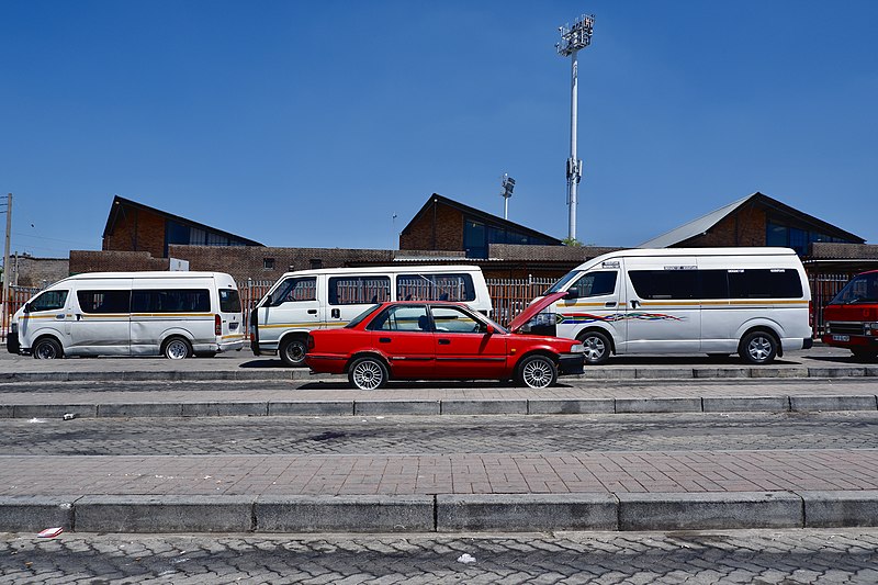 File:Red car against row of South African taxis.jpg